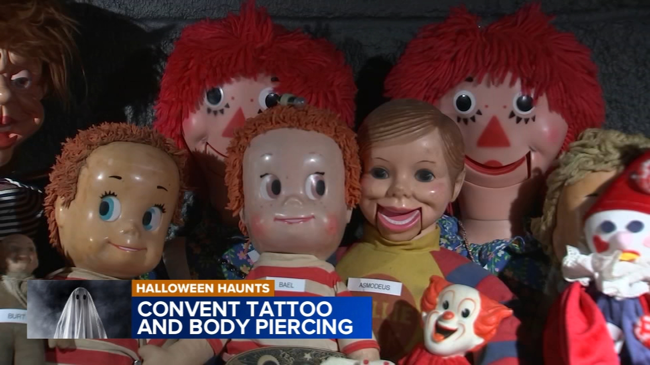 A lively tattoo shop decorated for Halloween, showcasing artists at work.